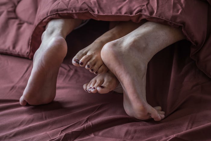 Legs of men and women are having sex on a brown bed.