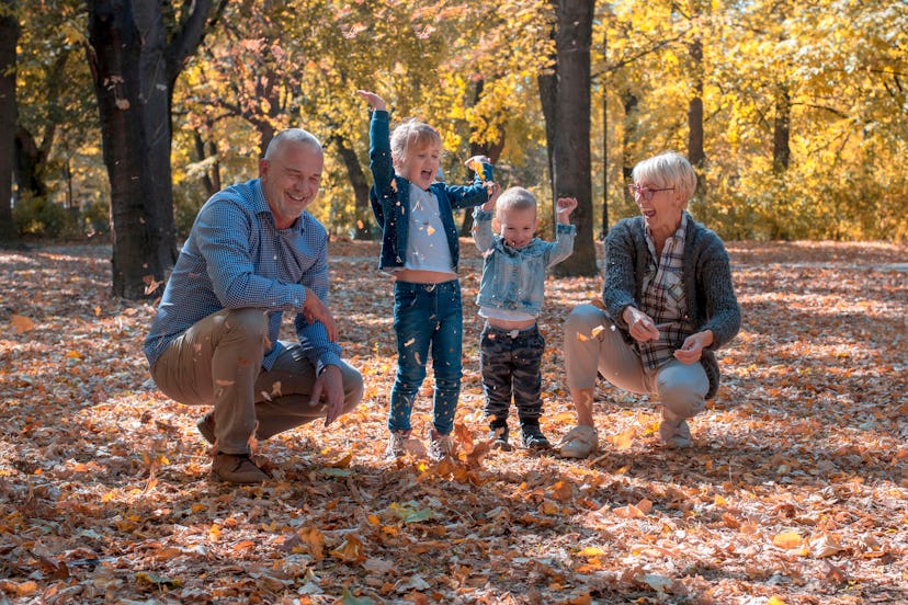 Grandchildren and grandparents throwing leaves in park and spending time together
