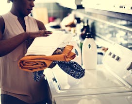 Black woman using washing machine doing the laudry