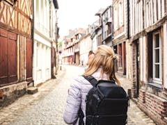 woman traveler with backpack on the streets of a quaint old town - slow travel