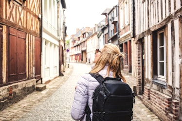 woman traveler with backpack on the streets of a quaint old town - slow travel