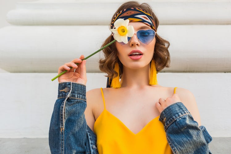 beautiful sexy woman in yellow stylish dress wearing denim jacket, holding flower, trendy outfit, hi...