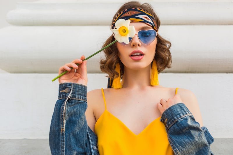 beautiful sexy woman in yellow stylish dress wearing denim jacket, holding flower, trendy outfit, hi...