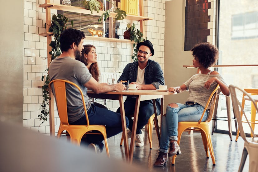 Young people sitting at a cafe table. Group of friends talking in a coffee shop.