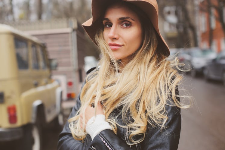 lifestyle portrait of young beautiful woman walking outdoor on city streets, wearing hat and leather...