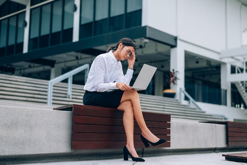 Asian businesswoman in eyeglasses using laptop working about business and finance feeling stressful-...