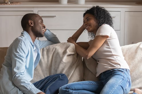 African couple sit resting on couch flirting enjoy romantic date, mixed race wife black husband havi...