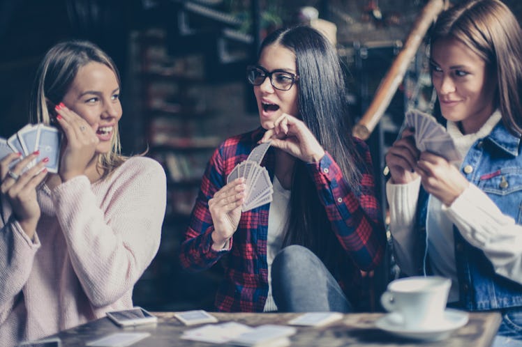 Three girls playing card in cafe.