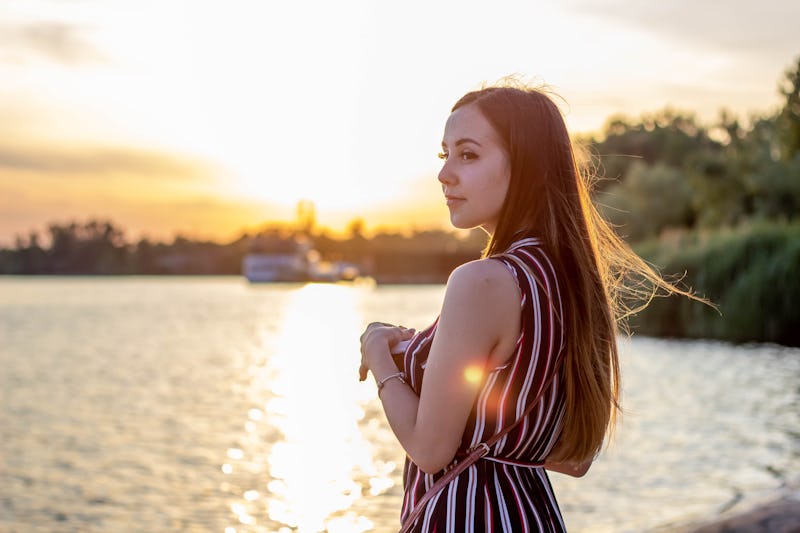 Girl drinks coffee at sunset off the coast.