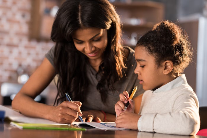 Mother and cute little daughter sitting at table and doing homework together at home, homework help ...