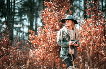 Beautiful girl with vintage camera in golden autumn forest