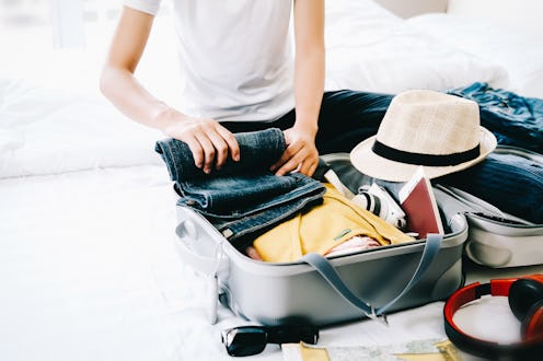 Woman packing travel bag for summer vacation. Tourism and objects concept, suitcase for summer holid...