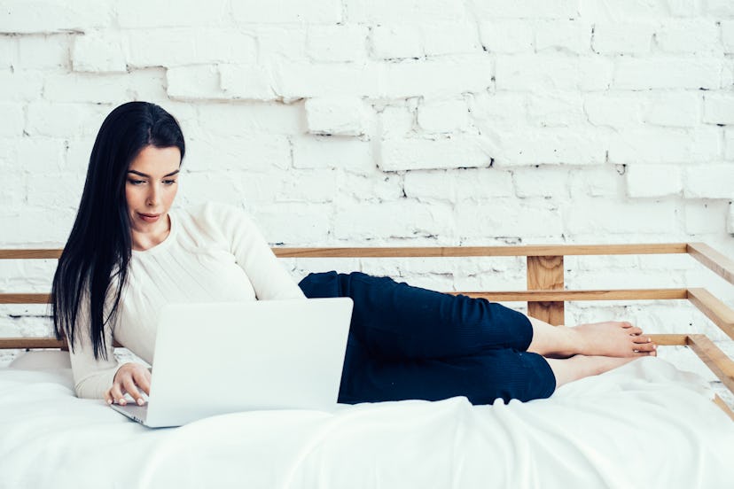 Woman with laptop on bed home natural lifestyle portrait