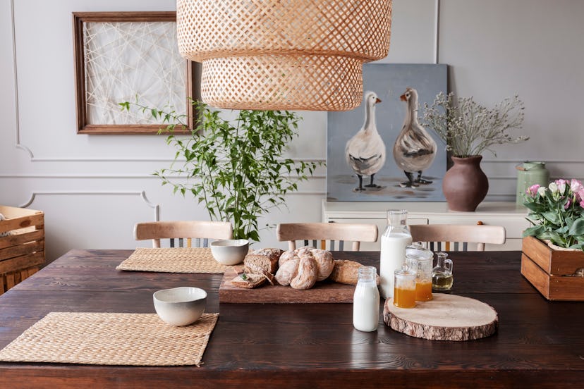 Lamp above wooden table with food and bowls in grey dining room interior with posters. Real photo