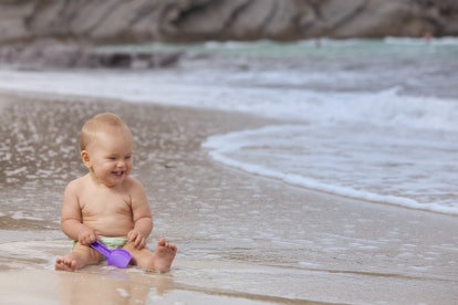 happy smiling baby girl playing on the beach.