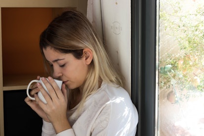 Woman drinking coffee near a window