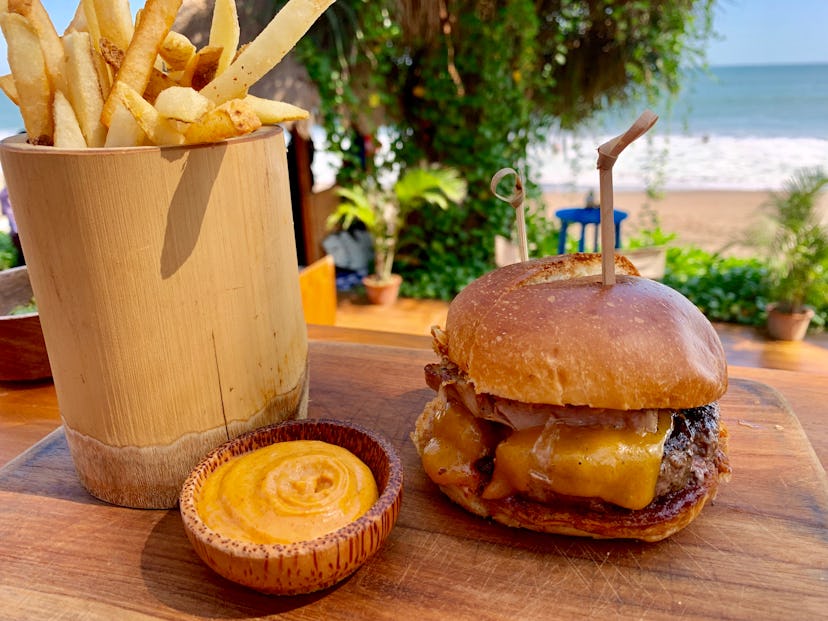 Brioche cheese burger with meat and BBQ rib meat, french fries and spicy mayo on a wooden presentati...