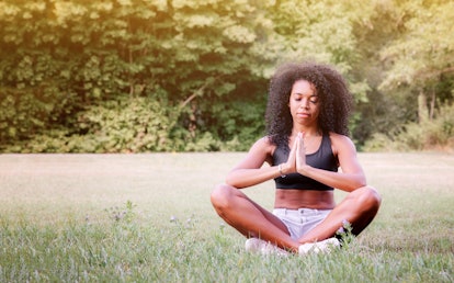 Young woman practices yoga and meditates in the lotus position in the park