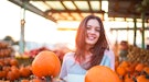 Young woman holding two pumpkins at a pumpkin patch, in need of Instagram captions for pumpkin patch...