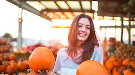Young woman holding two pumpkins at a pumpkin patch, in need of Instagram captions for pumpkin patch...
