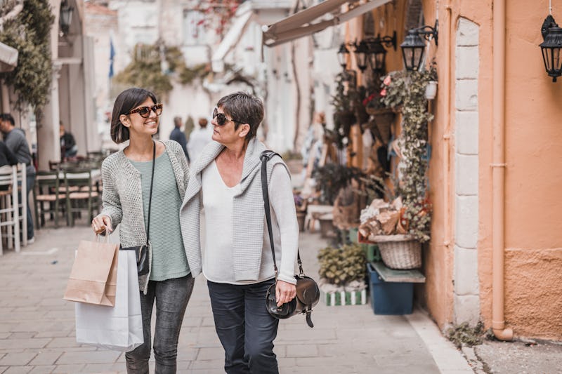 Beautiful young daughter and older senior mother outdoors in beautiful old town shopping and looking...