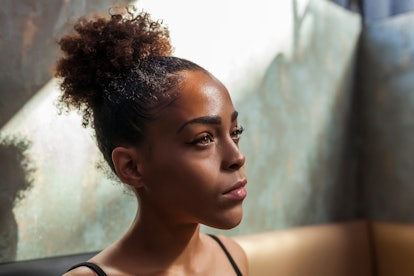 Young, afro, serious and sad woman posing sitting with natural sunset light