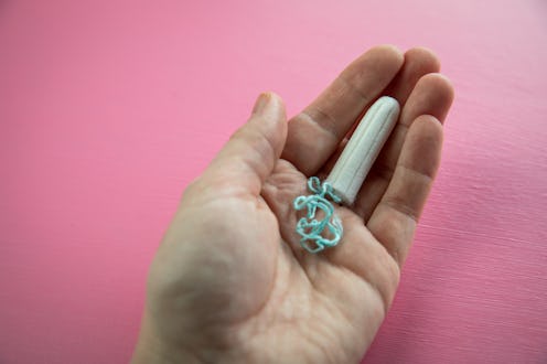 Woman with tampon on pink background for female personal hygiene and protection during menstruation ...