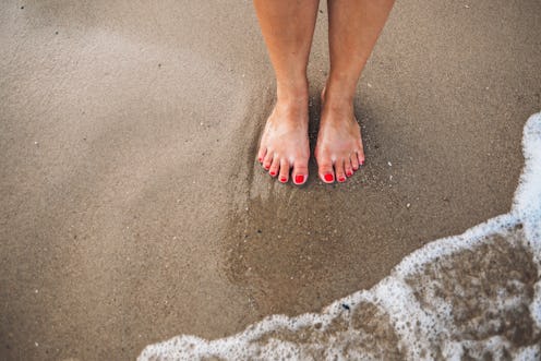 Female feet with red polish on nails on the beach