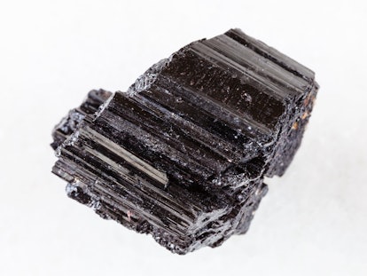 macro shooting of natural rock specimen - raw crystal of black Tourmaline (Schorl) gemstone on white...