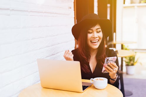 Young fashionable business woman watching her smart phone in excited and successful moment at cafe r...