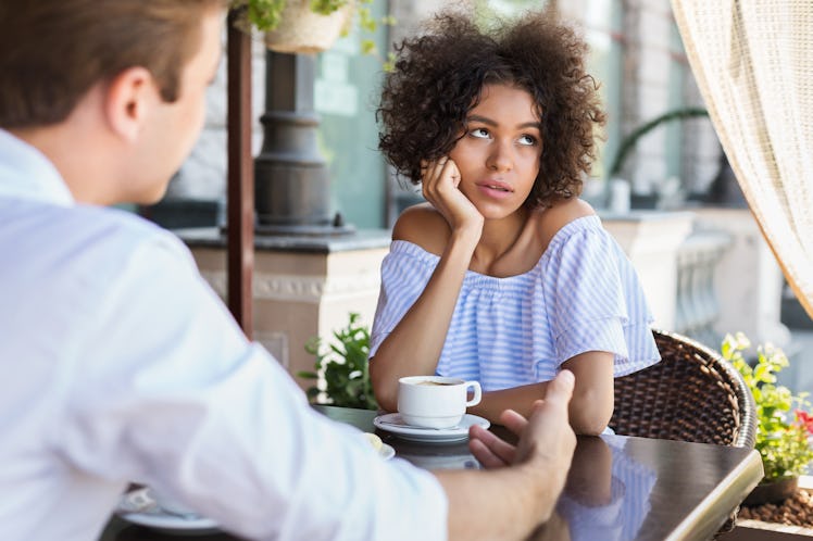 Black woman disinterested with blind date at outdoor cafe