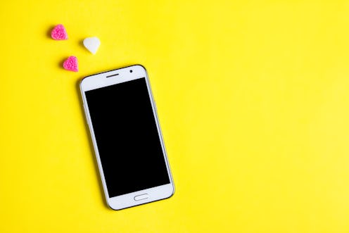 Top view of mobile cellphone and pink heart on art paper background, copy space. Mockup template for...