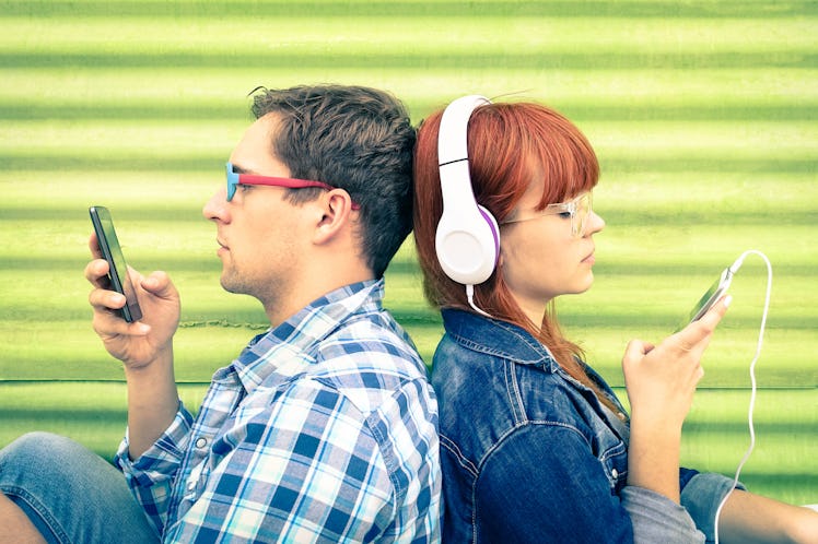 Hipster couple in disinterest moment with mobile phones - Concept of apathy sadness and isolation us...