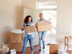 Female Friends Carrying Boxes Into New Home On Moving Day