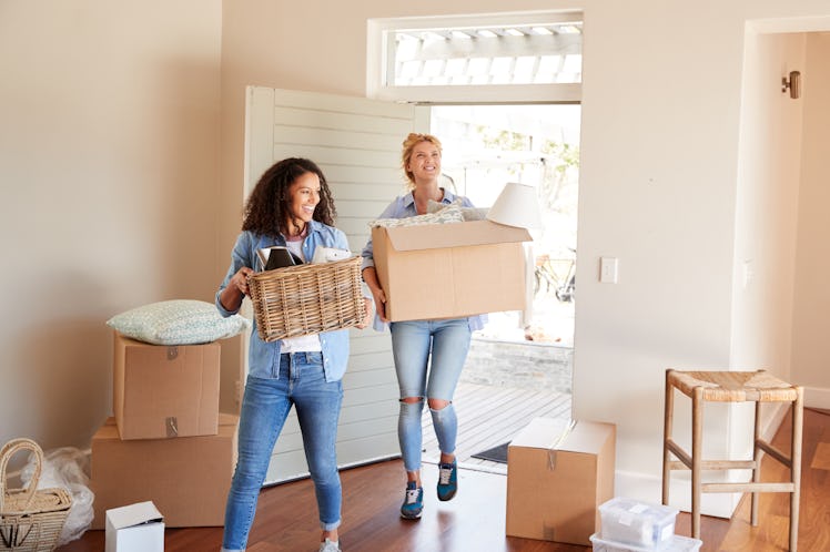 Female Friends Carrying Boxes Into New Home On Moving Day