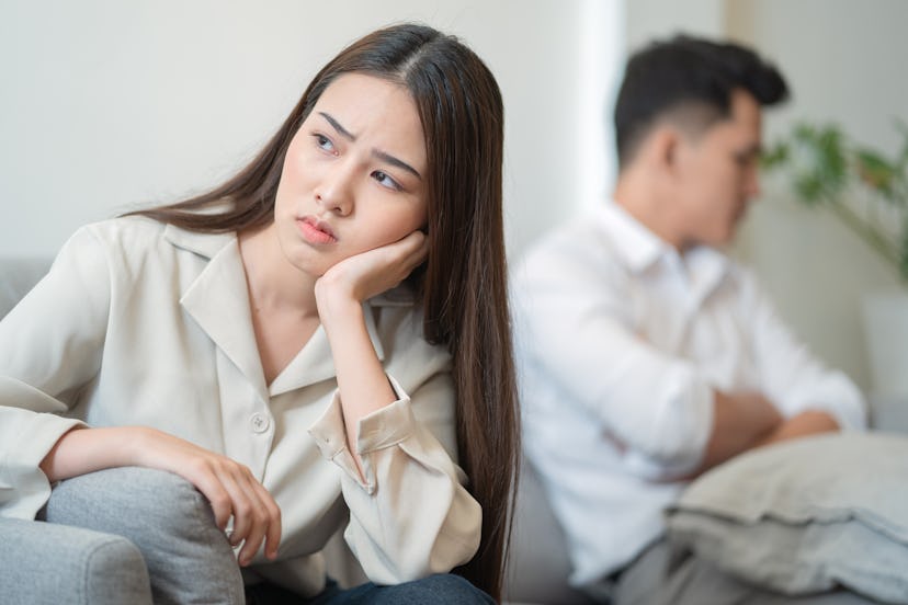 Young couple in quarrel at home.sadness young Asian woman sitting on sofa with boyfriends.relationsh...