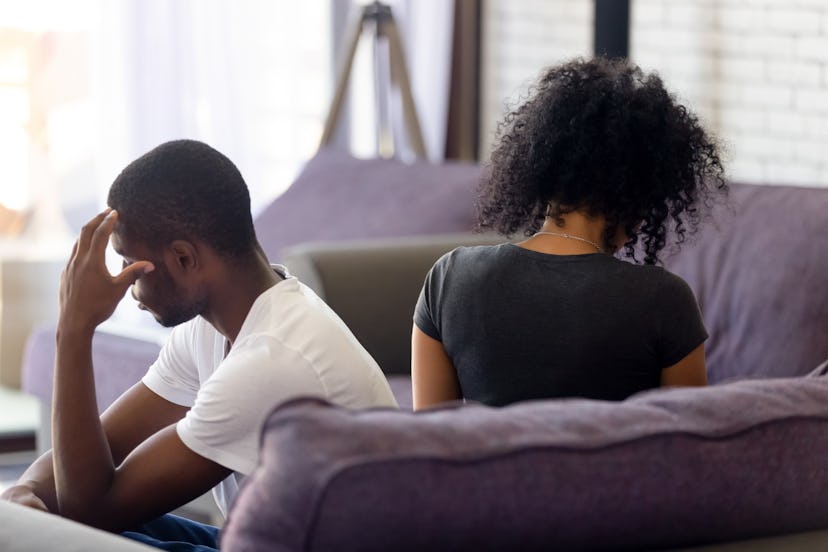 Unhappy african american married couple rear view, spouses sitting on sofa at home wife and husband ...