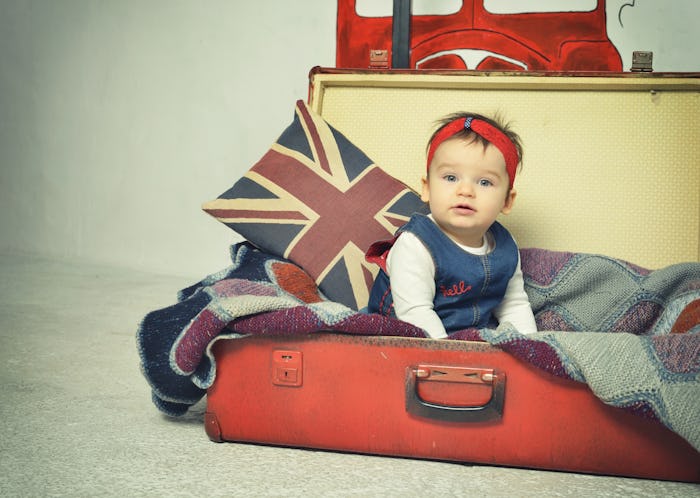 Cute Baby girl sitting in old vintage suitcase