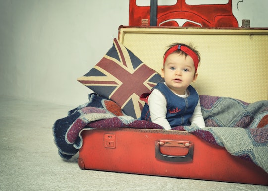 Cute Baby girl sitting in old vintage suitcase