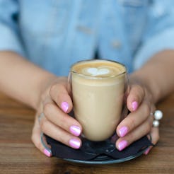 A glass of cappuccino in female hands  