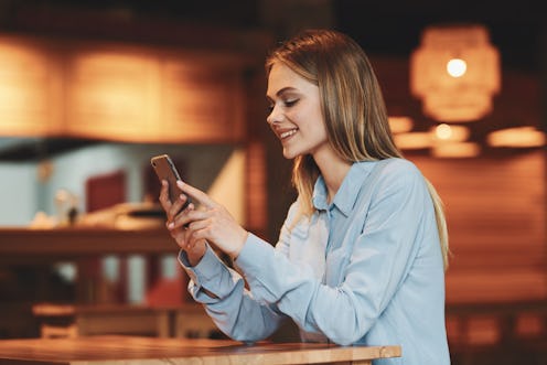 woman with phone smiling at cafe