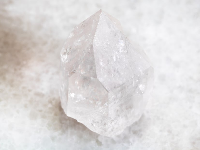 macro shooting of natural mineral rock specimen - rock crystal of quartz gemstone on white marble ba...
