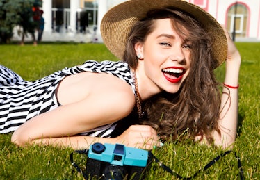 Outdoor lifestyle portrait of stylish girl laughing and smiling holding retro camera.Beautiful sexy ...