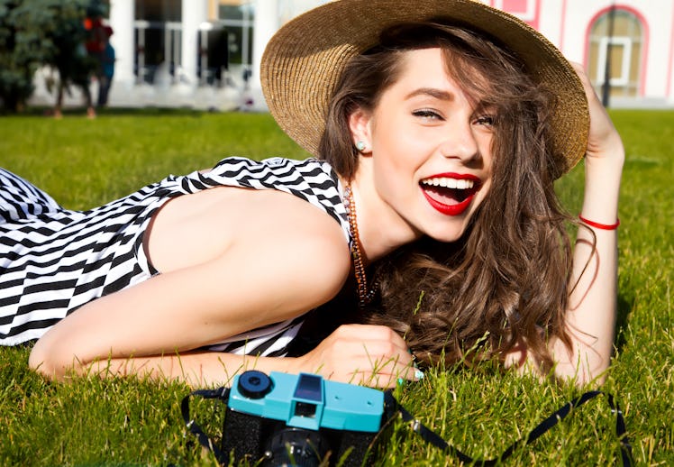 Outdoor lifestyle portrait of stylish girl laughing and smiling holding retro camera.Beautiful sexy ...
