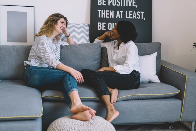 Cheerful african american young woman laughing together with best caucasian friend during funny conv...