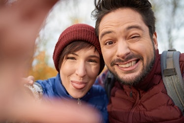 Couple of Canadian millennials taking selfies with a smartphone in a fall forrest