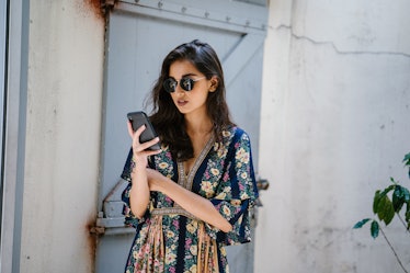 Portrait of a young, attractive and beautiful Indian Asian woman wearing a dress and sunglasses with...