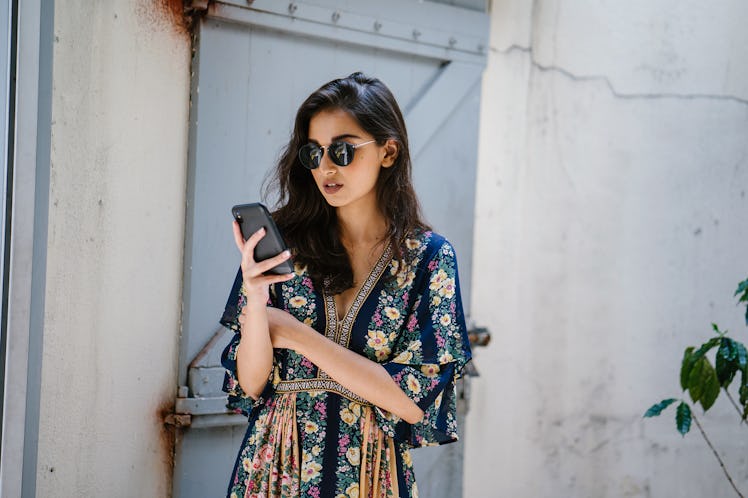 Portrait of a young, attractive and beautiful Indian Asian woman wearing a dress and sunglasses with...