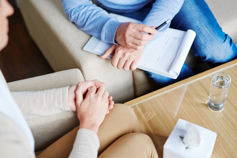 Middle-aged psychologist sitting next to his patient and listening to her childhood story in order t...