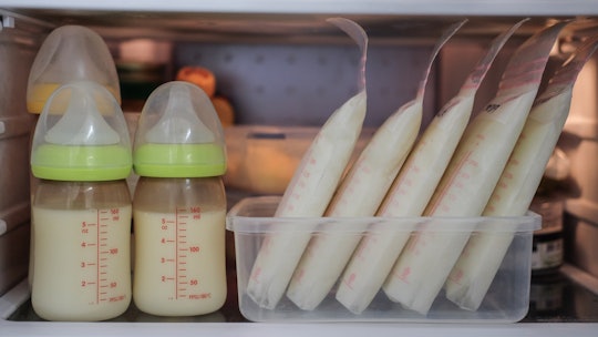 Baby bottle with milk and frozen breastmilk in storage bags in refrigerator
